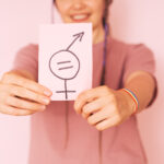 Girl holding paper with gender equality sign against pink background
