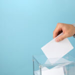 Man putting ballot into voting box on blue background