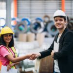 Team engineers and foreman stack hand and shake hands to show success at factory machines. Worker industry join hand for collaboration.